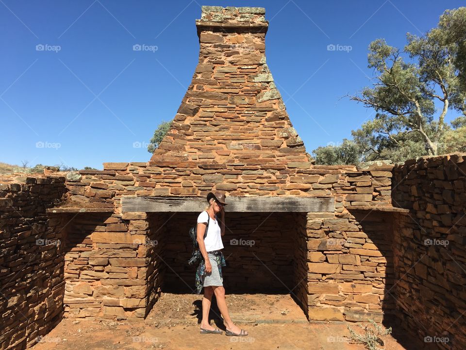 Female photographer standing in front of fireplace at old settlers ruin in the Flinders Ranges outback of South Australia 