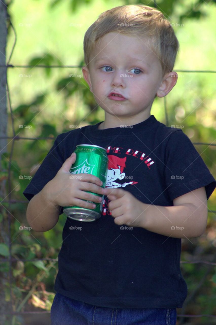 Portrait of a boy holding drinks can