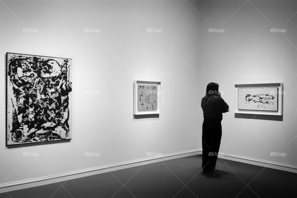 A woman looking at paintings at a Jackson Pollock exhibit at the Dallas Museum of Art squares