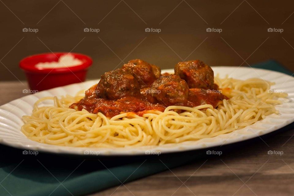 spaghetti served on a while plate placed on a wood table
