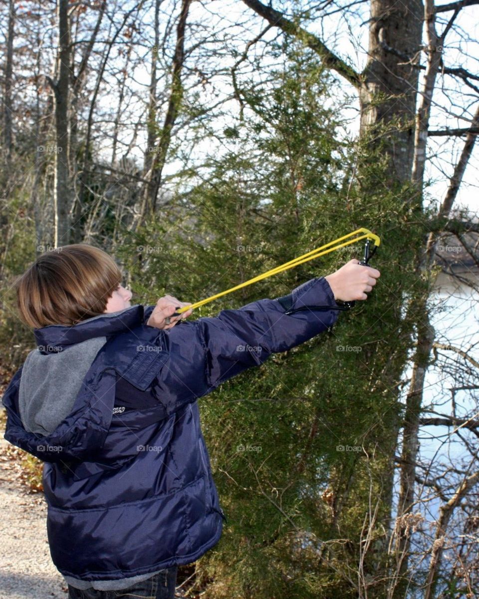 young boy shooting a slingshot / kid with slingshot