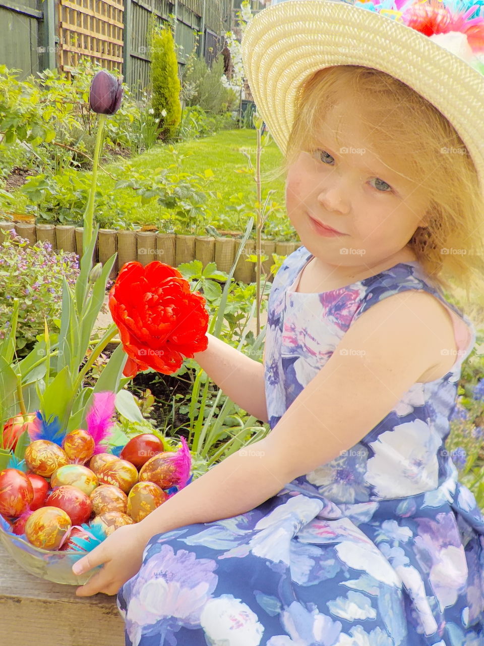 Pretty girl with bowl of Easter egg and red flower