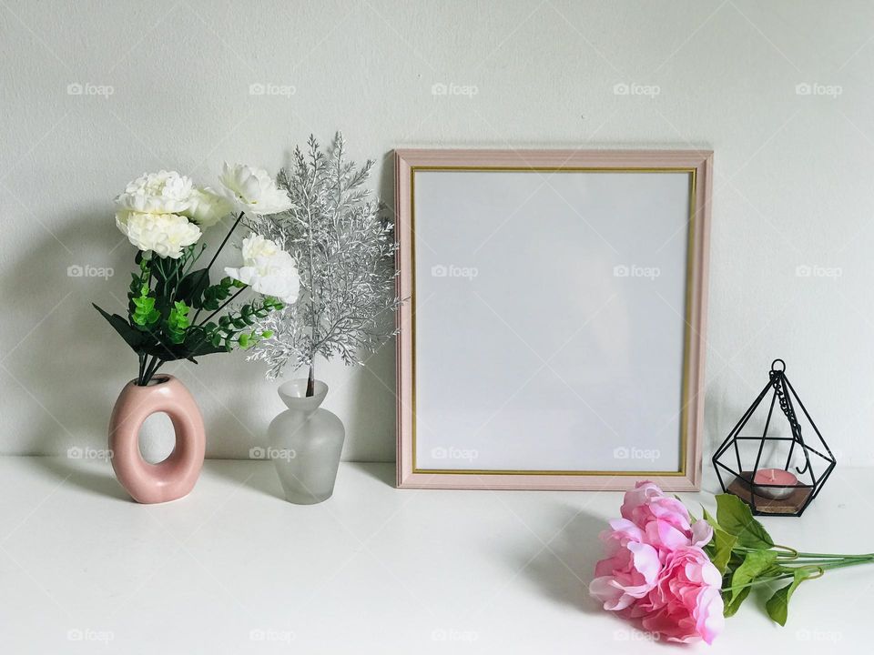 A beautiful pink photo frame and bunch of pink flowers along with pink vases and pink candle in holder on white table looking very pretty π