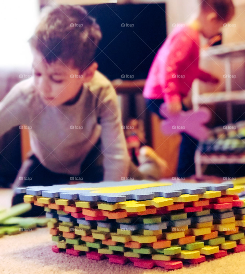 Kids playing with colorful foam puzzle letters. 