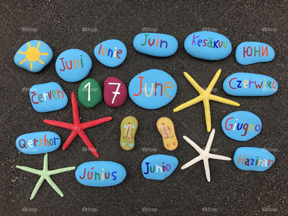 17 June, calendar date with multicolored stones and starfishes over black volcanic sand