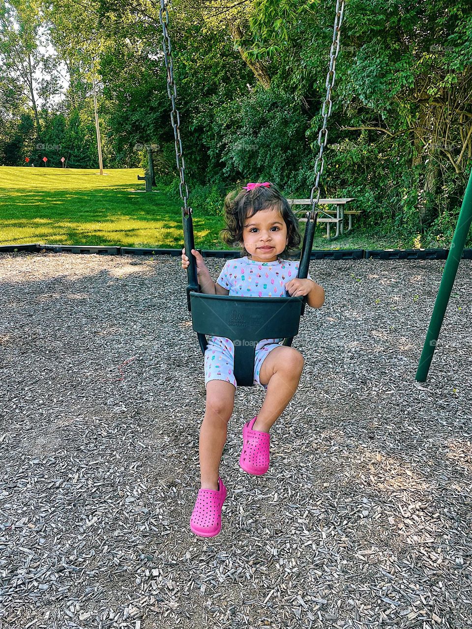 Portrait of a toddler on a swing, toddler girl on a swing, toddler girl at the park having fun, toddler swinging at the park, toddler and mommy time, toddler has fun outside, toddler girl at the park with mommy 