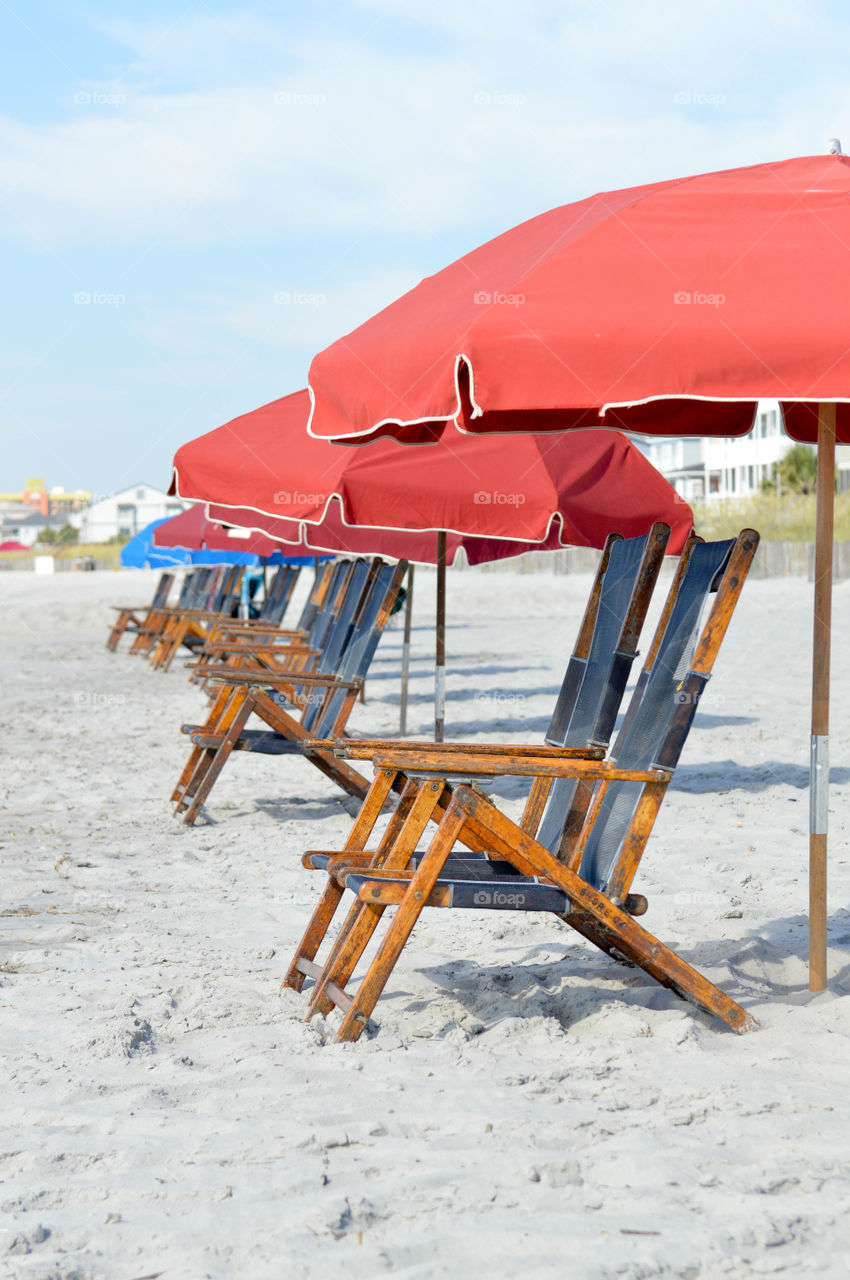 Row of chairs and umbrellas set up on the beach with no people