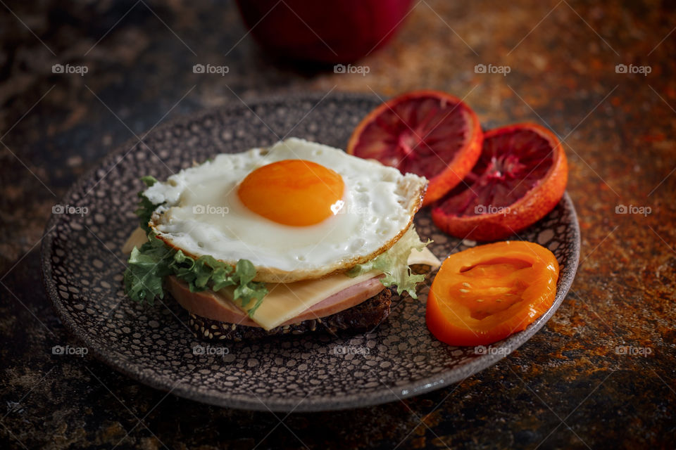 Sandwiches with fried egg orange tomato and red orange fruit 