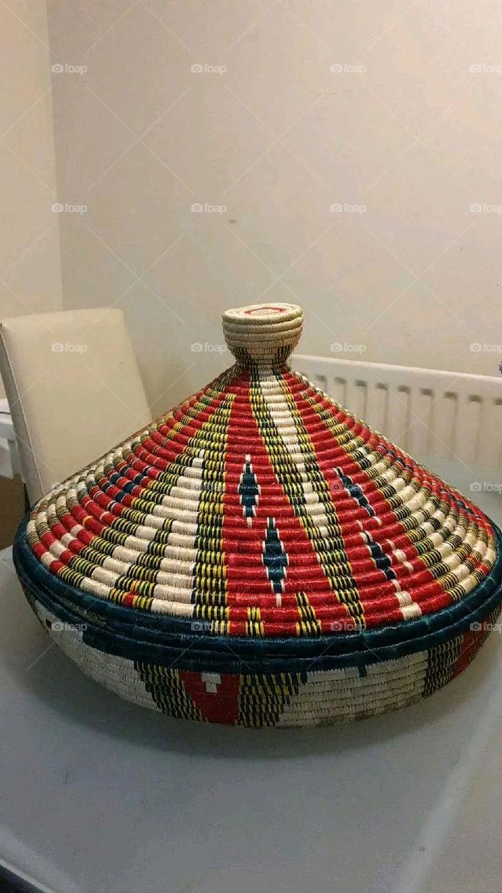 The image shows a group of hand -made dishes of wicker, decorated with colored embroideries with beautiful floral shapes, and is elegantly displayed in a warm corner that combines heritage and beauty, which gives the place an artistic spirit and attr