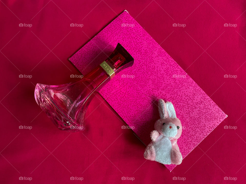 Pink still life with envelope, bunny and perfume bottle.