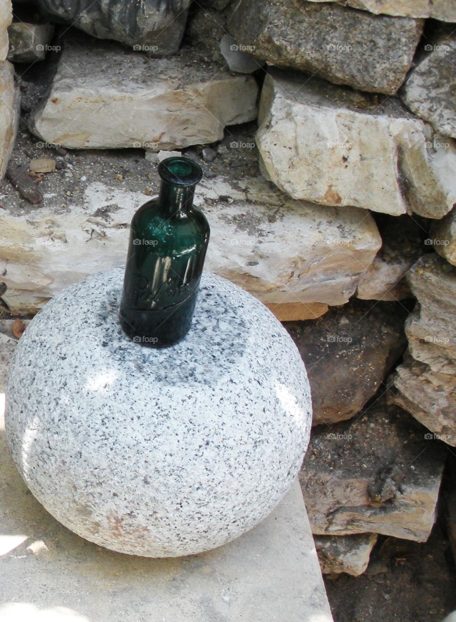 green glass bottle surrounded by stonework in California