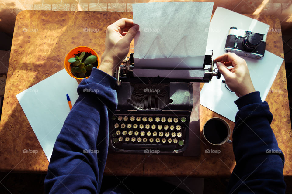 A young writer is writing a new book on an old typewriter.