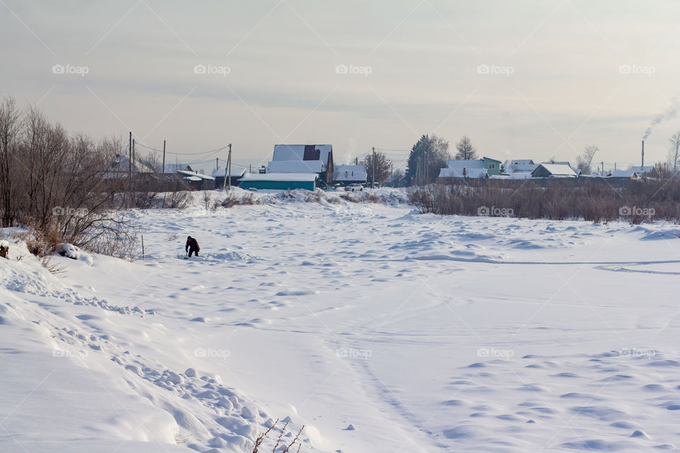 Houses in the background of the frozen river.