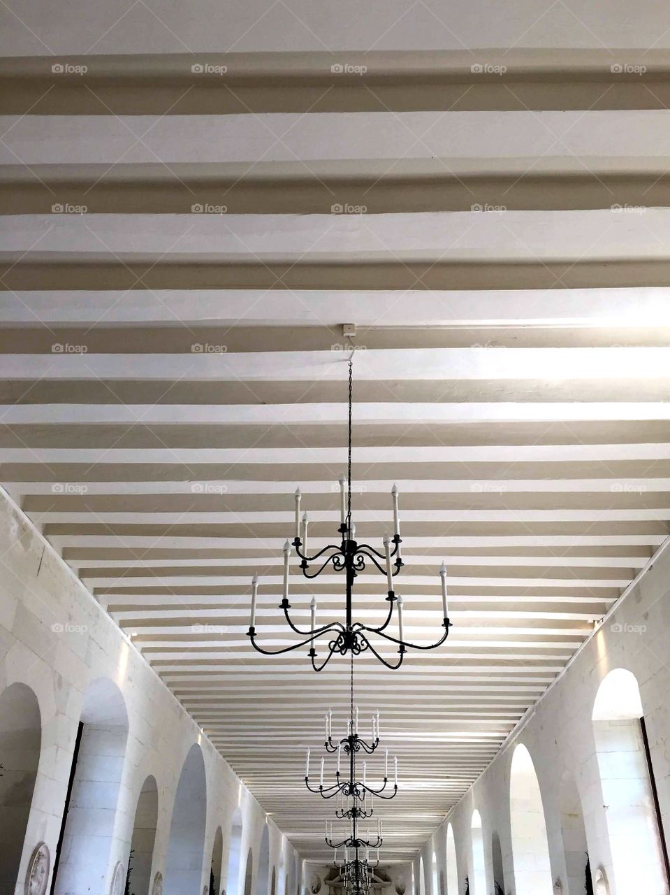 White striped ceiling with black metal lamps goes into the distance. Perspective. Interior. Gallery