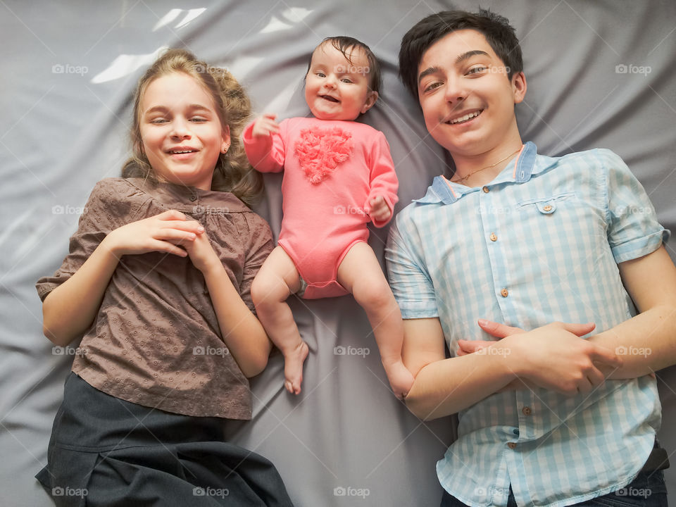 Loving siblings having fun together. Boy and girl playing with their little sister