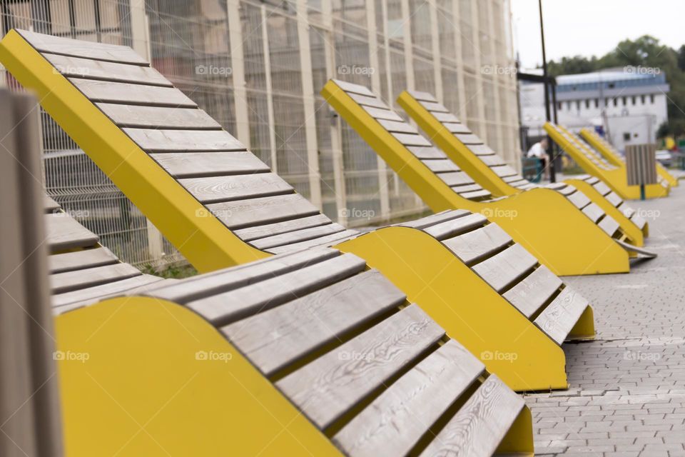 Yellow, wooden benches on the street of a modern city