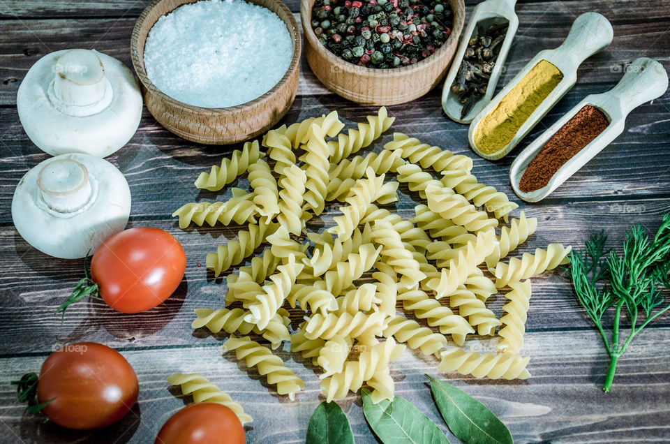 Raw pasta with ingredients and wooden accessories