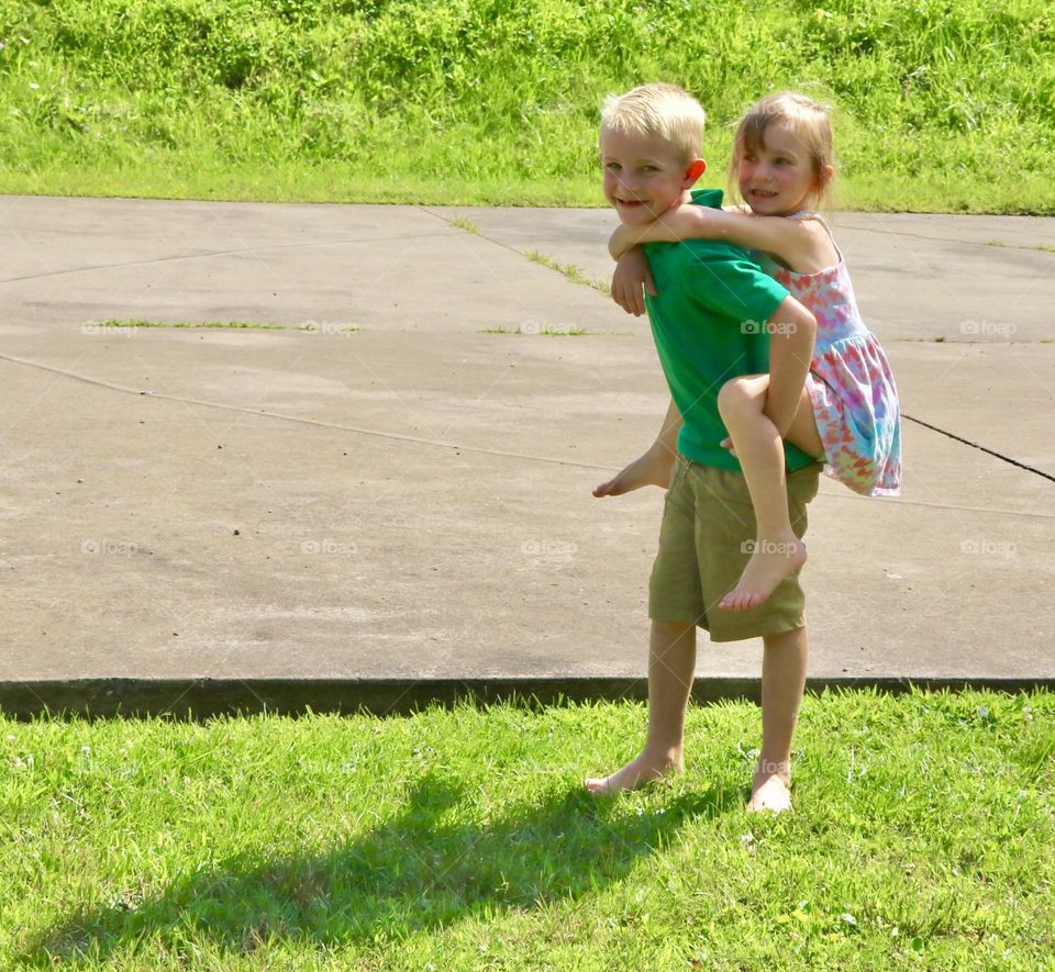 Summer clothes, brother giving sister a piggyback ride