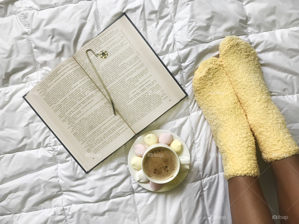 Coffee and book in cozy bed in cozy socks 