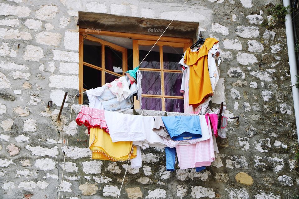 Old stone house, window slightly open and colourful clothes hanging out on fresh air