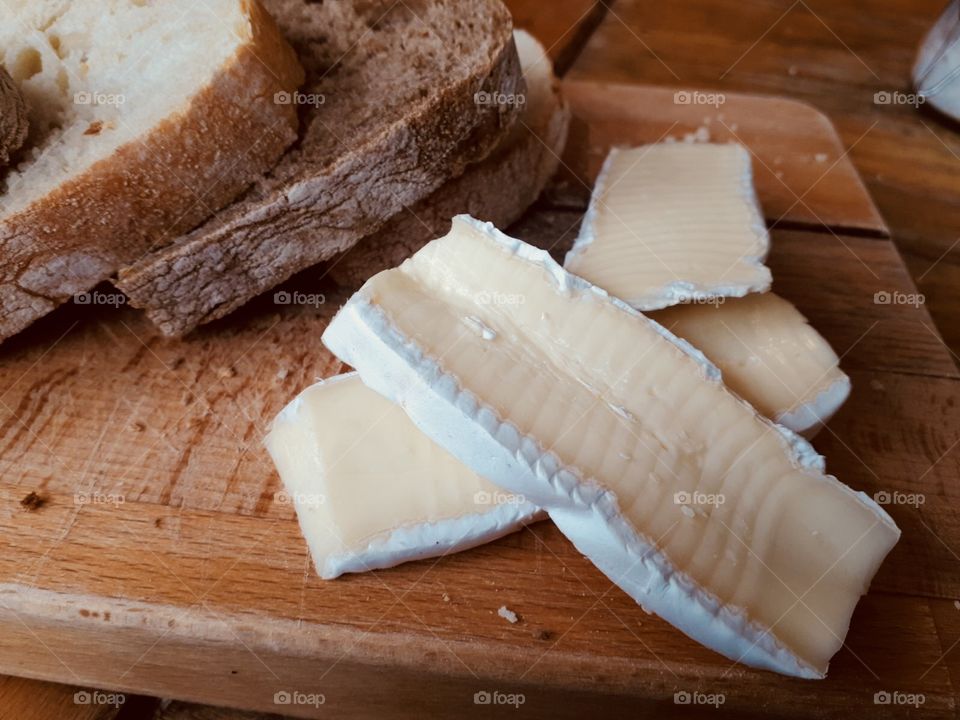 Wooden plate with snacks: rustic bread and some french brie cheese