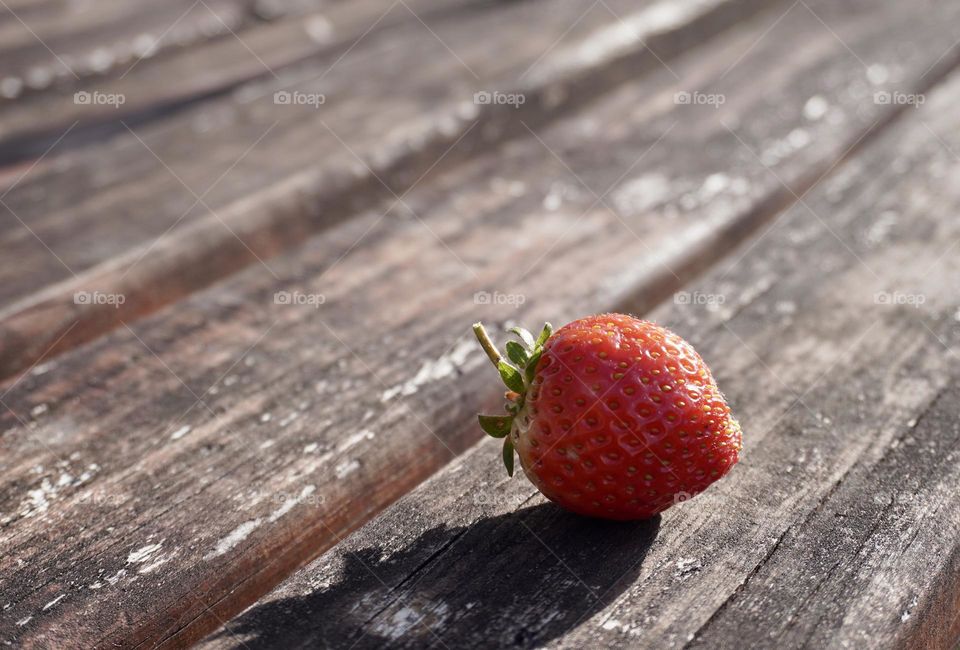 Fresh red strawberry on a wooden bench