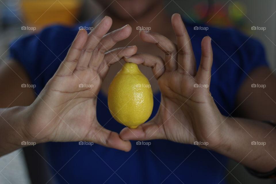 Young woman holding lemon in hand 