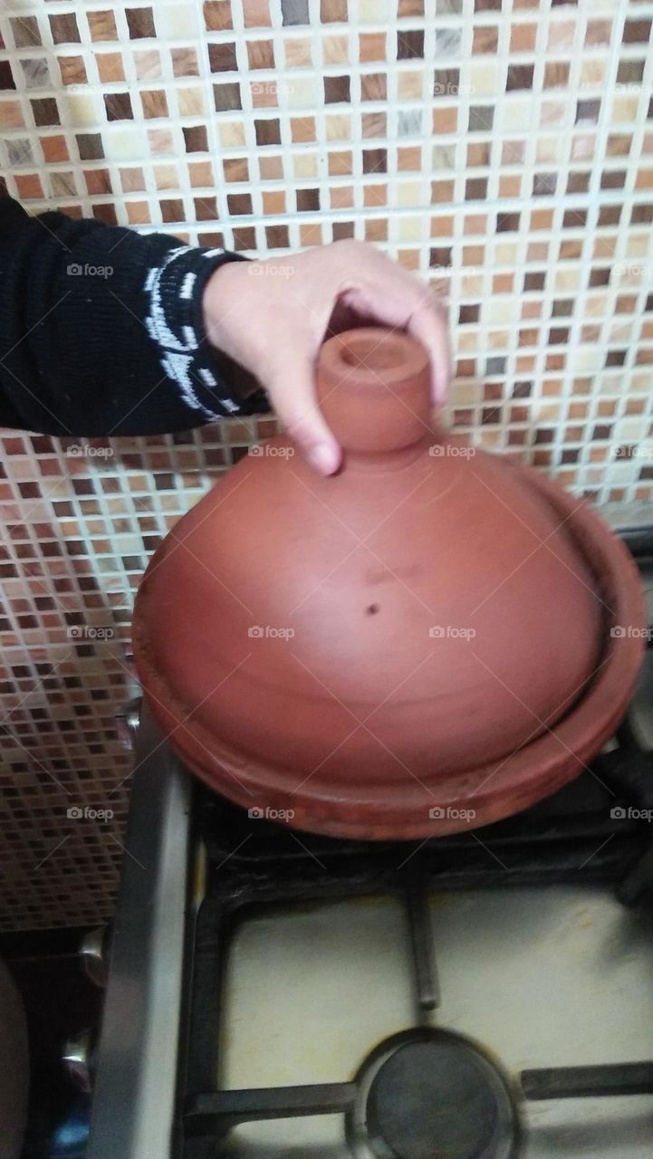 beautiful hand of my mother tries to open Moroccan Tajine food.