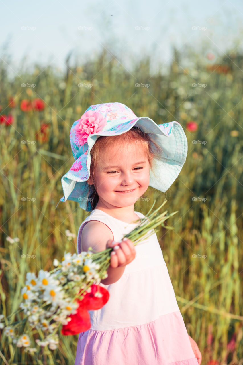 Lovely little girl in the field of wild flowers. Cute girl picking the spring flowers for her mom for Mother's Day in the meadow. Spending time close to nature