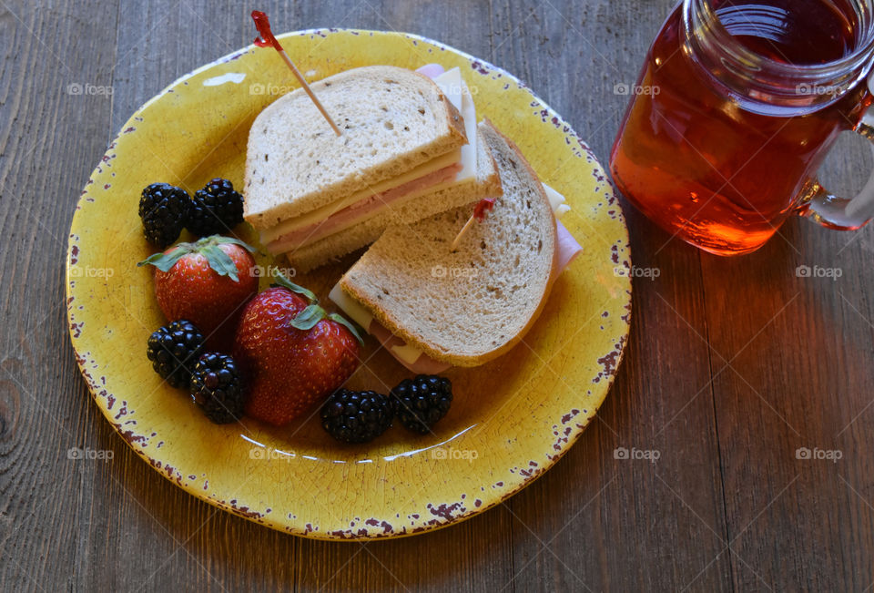 Ham and cheese sandwich with fruit and a glass of juice