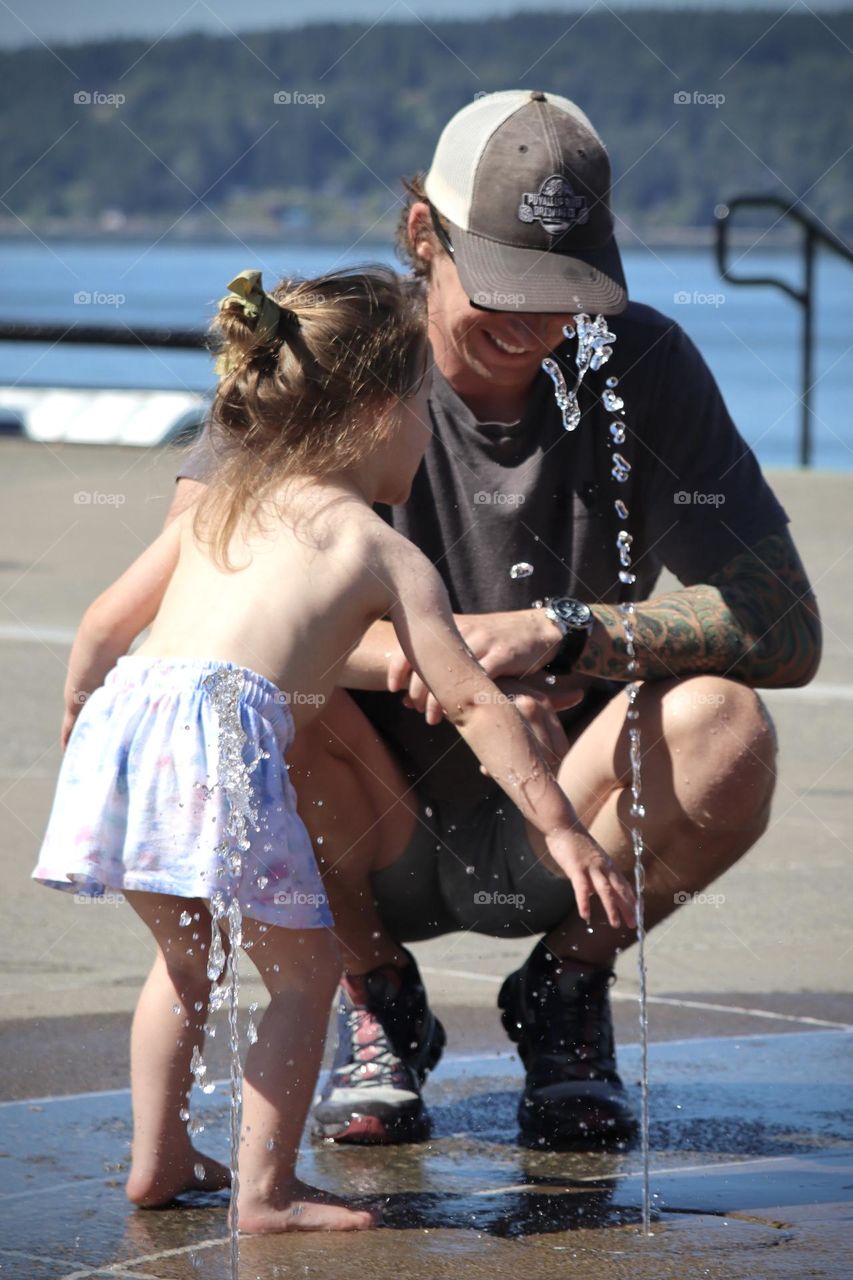 A father and his young daughter have fun playing in the water at Point Ruston, Tacoma on a summer day