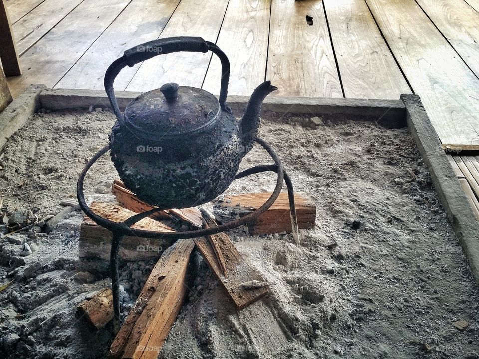 The kettle is set in a place for boiling water.  It's a cozy atmosphere  In a rural one in Thailand.