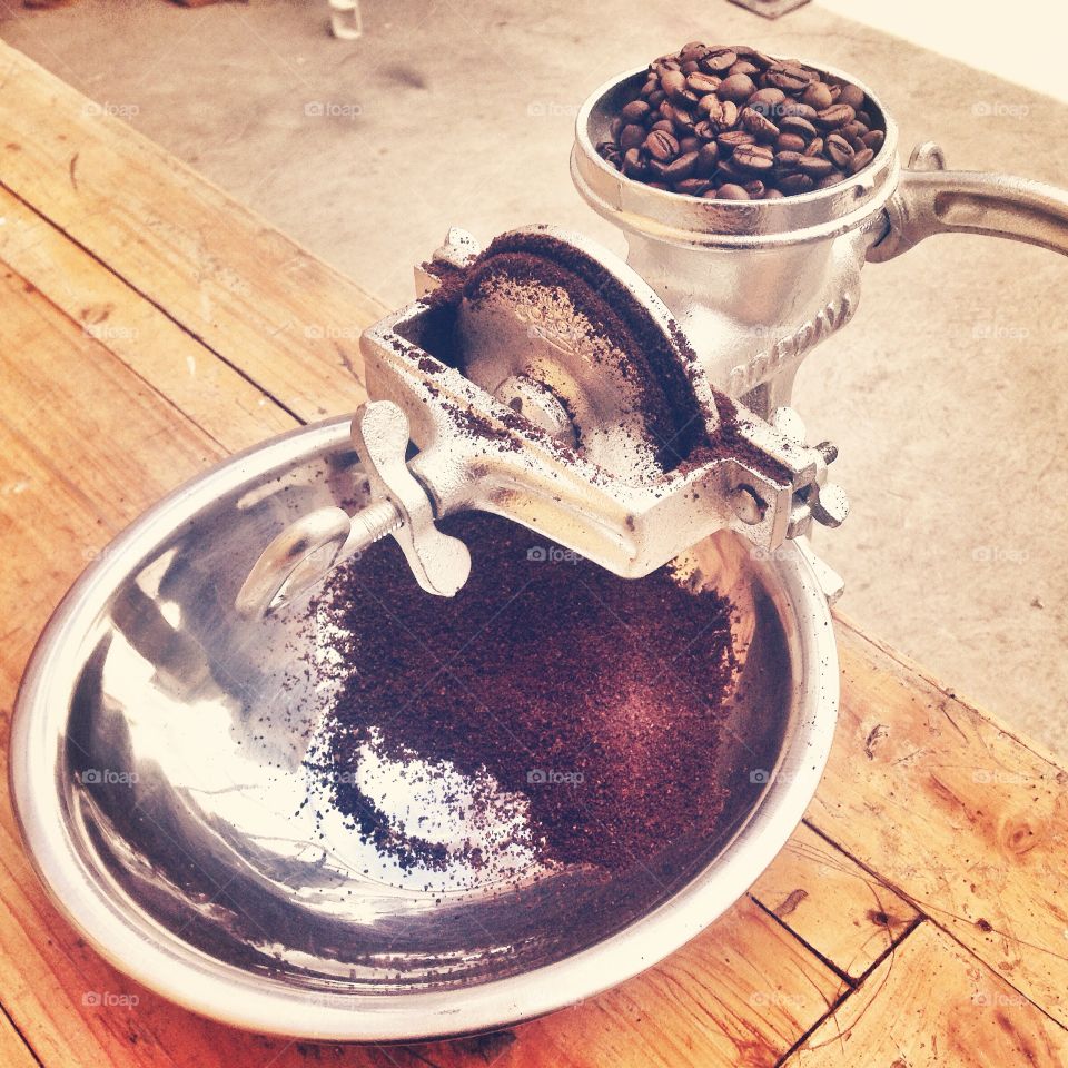 Fresh roasted coffee beans being ground in a vintage hand grinder