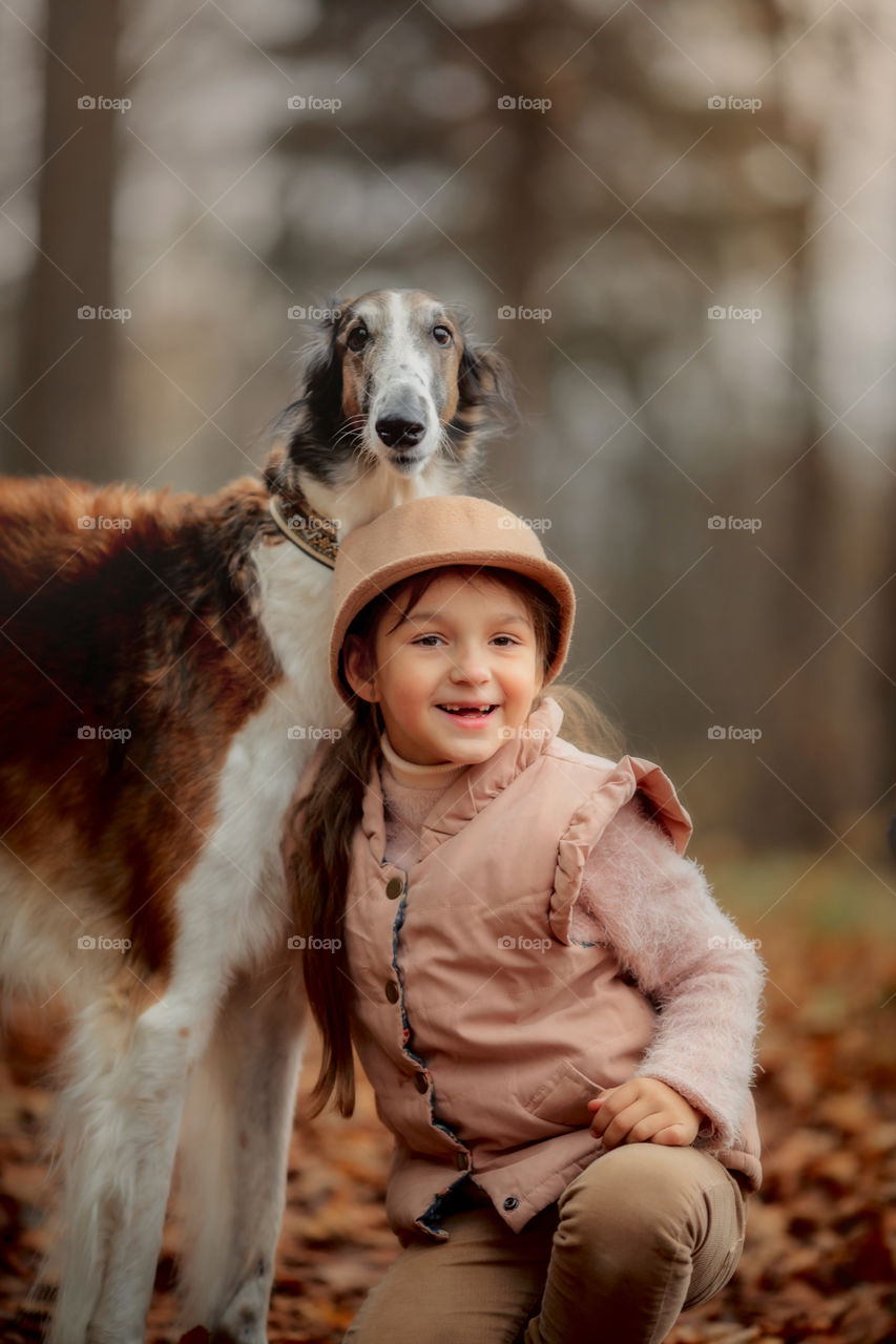 Cute smiling girl with borzoi dog in an autumn park 