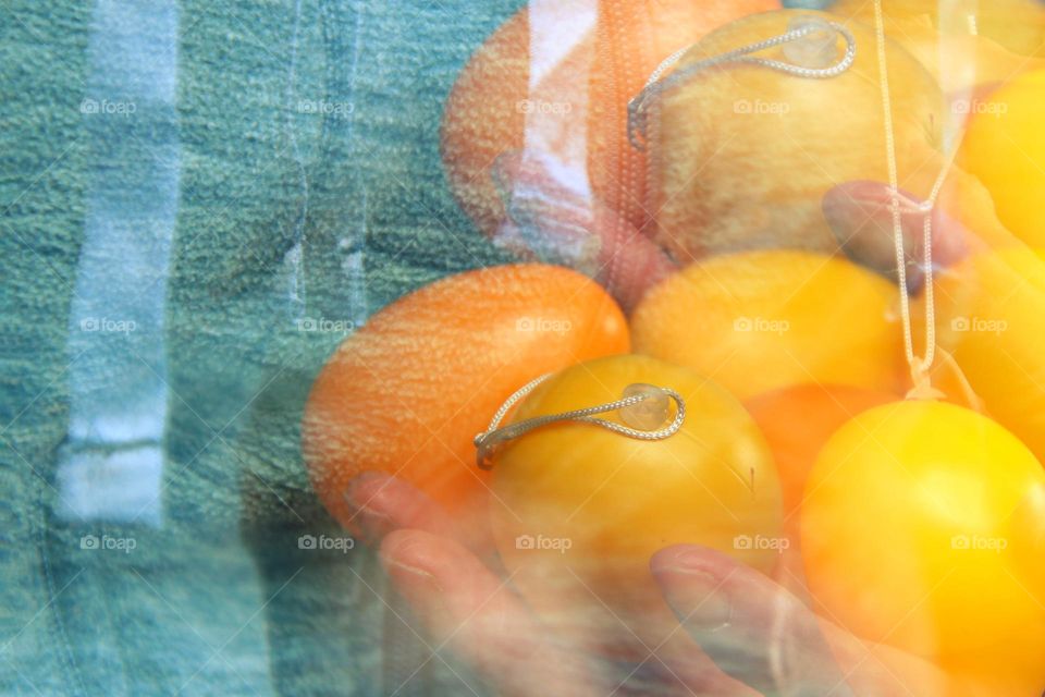 Close-up of double exposure yellow easter eggs in hand against blue background