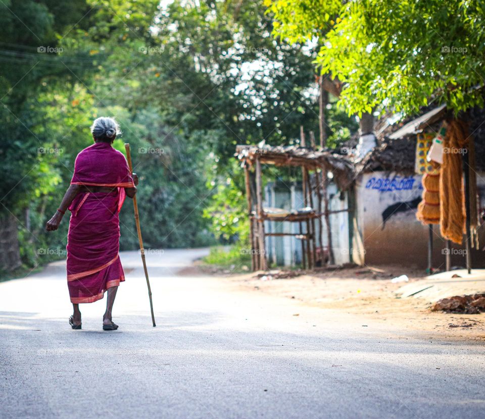 A photo that shows an old age women who walks from one place to another place even she is not able to walk properly... the stick help them to walk