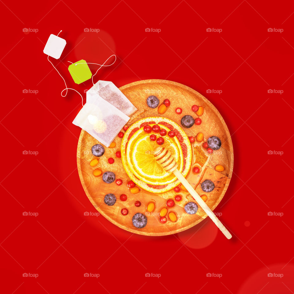 Immune boosting natural drink. with two tea bags, berries, citrus fruits and honey on a wooden plate. Homemade natural remedy for immunity and against viruses