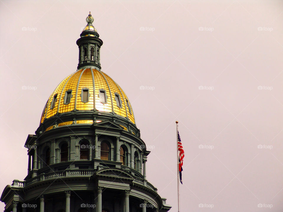 Gold Dome. Gold dome of the Colorado State Capitol glowing in the sunlight with a storm cloud backdrop.