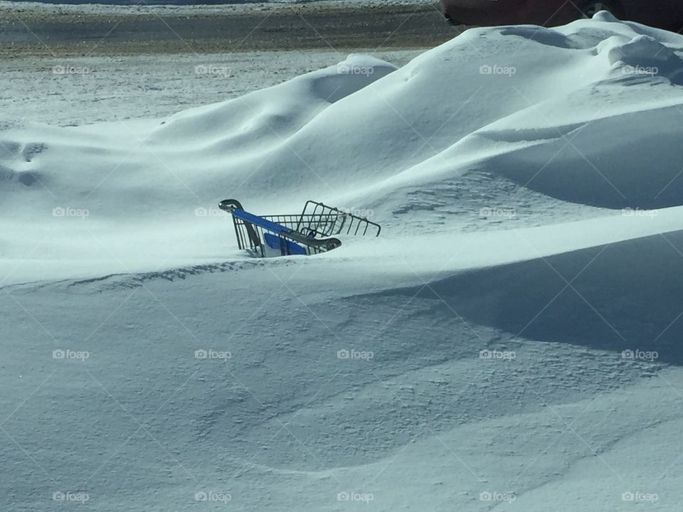 Shopping cart buried under snow.