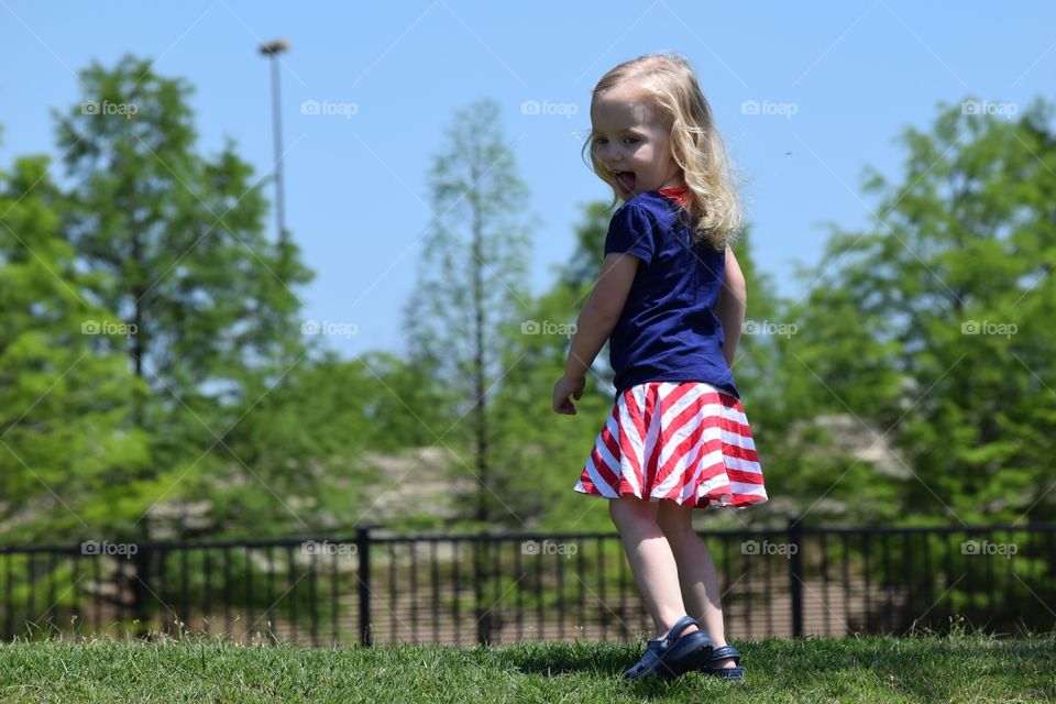 Toddler girl at the park. Girl in red, white and blue