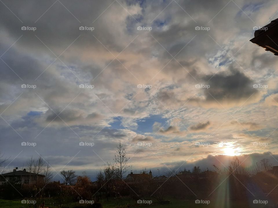 late autumn sunset with sunrays and reflection on clouds