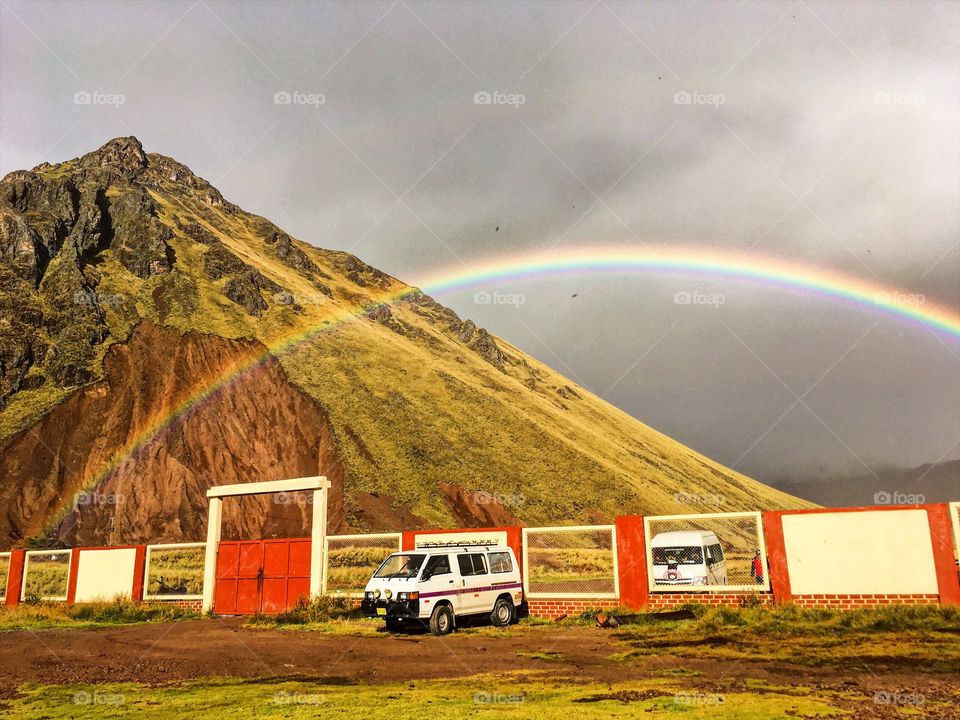 Camping in a van under a rainbow, next to the mountains. 