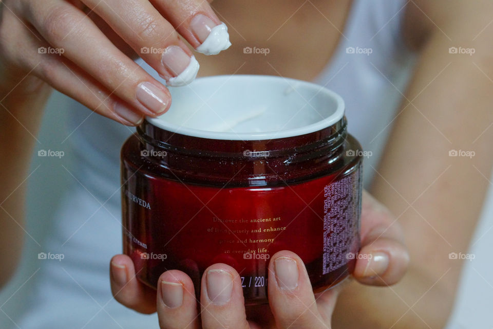 a woman holds a red cream jar in her hand