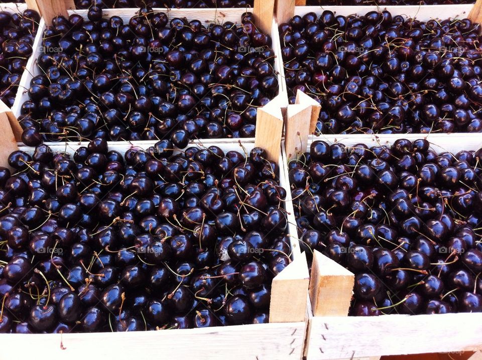 Black cherries in wooden boxes for sale.