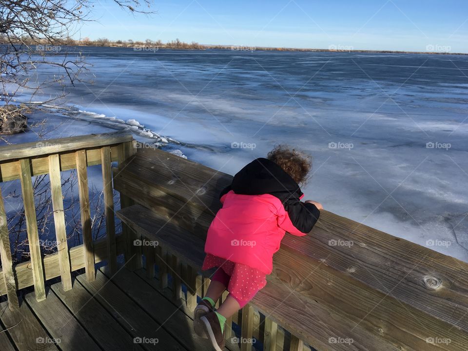 Little girl looking at frozen lake 