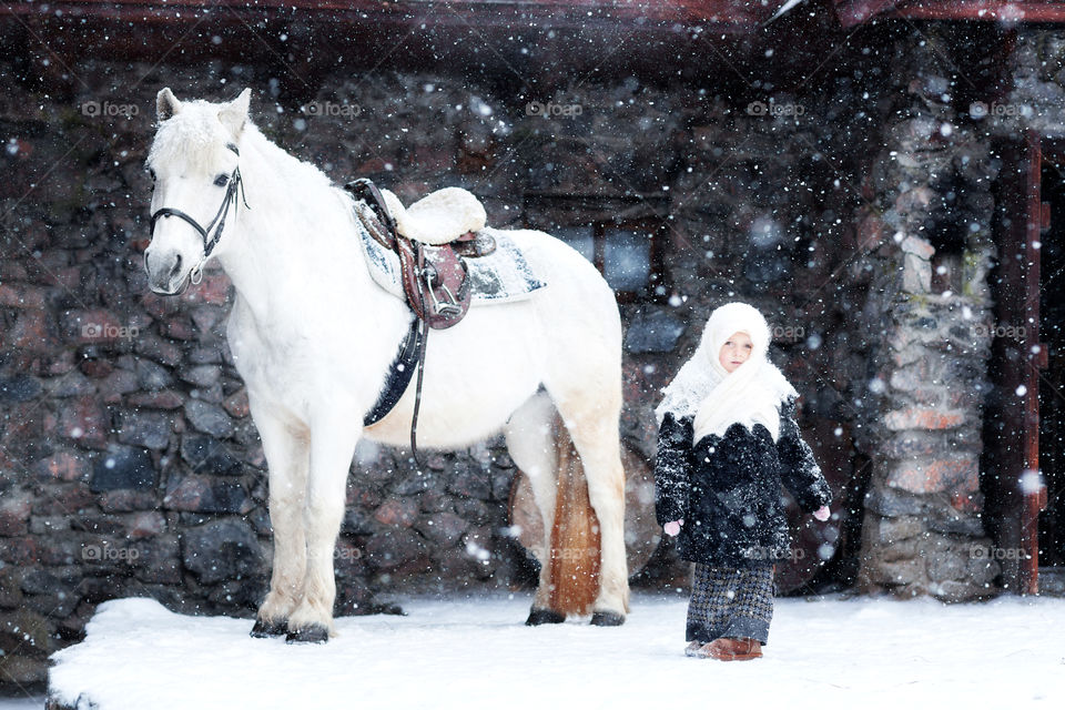 Portrait of cute little girl with white horse outdoor 