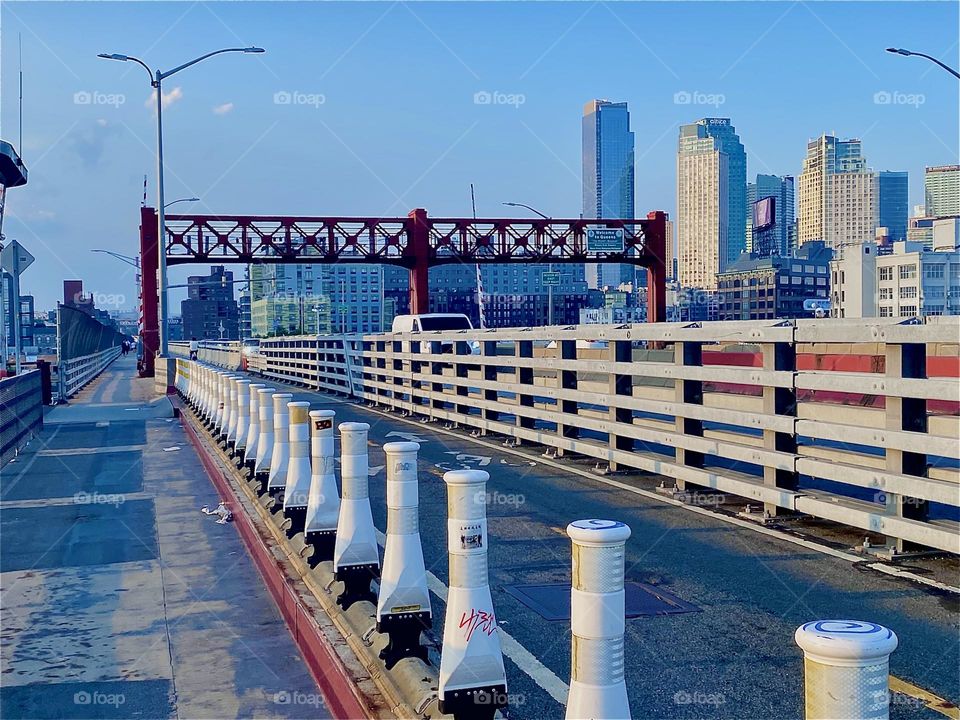 Walking across the „Pulaski Bridge“ in the pedestrian lane from „Greenpoint“, Bklyn to LIC, Queens reveals motifs of unequalled beauty. The red metal structure is ornate in a minimal way. The skyscrapers of LIC accentuate the pic. 2023. Hypnotic Prod