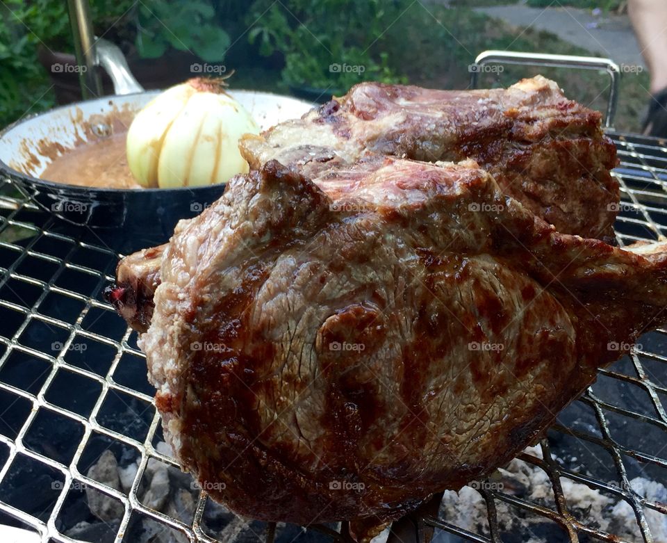 Bone-in ribeyes and onion on a cowboy grill