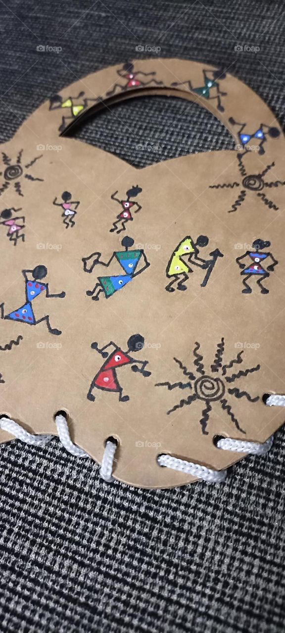 warli art made on a brown paper mini paper bag with complementary colors.