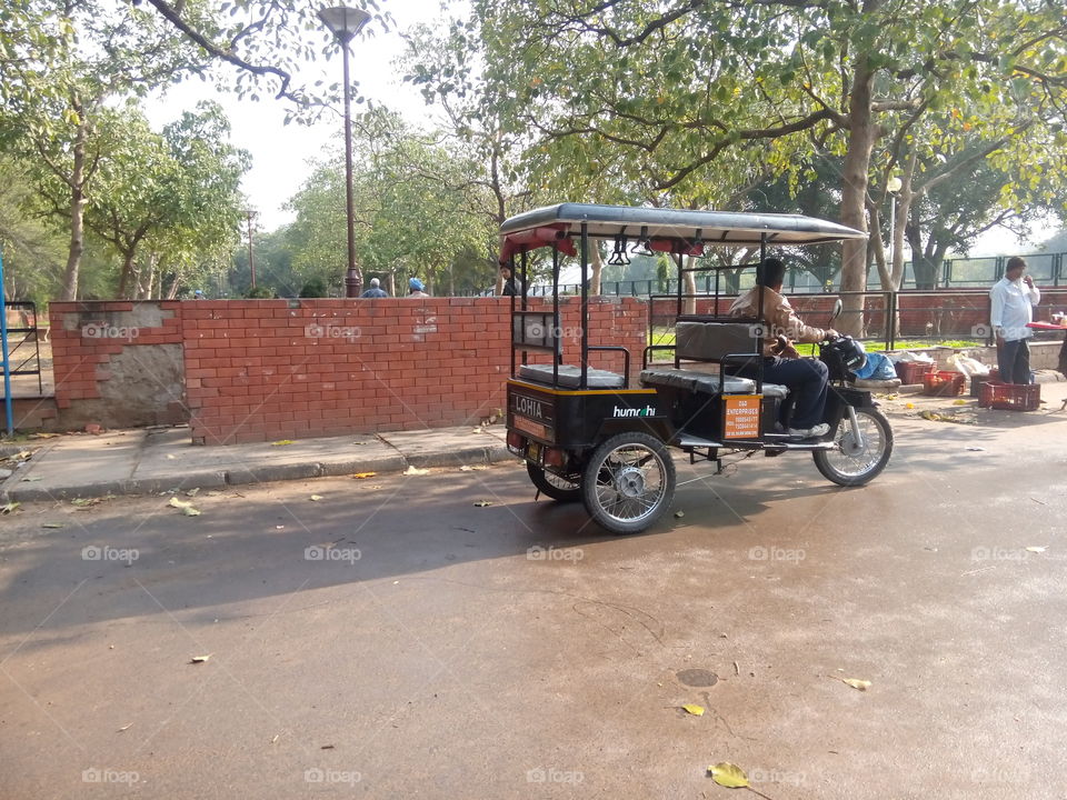 three-wheeler automobile driving walls parkway trees poll men
